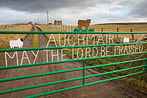 Religious message on farm gate with croft in background, Aberdeenshire, Scotland, UK, January 2017