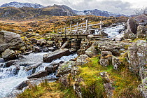 Bridge across waterfall near Llyn Ogwen on the path to Llyn Idwal and the Devil's Kitchen in the Glyderau mountain range Snowdonia North Wales, UK, February.
