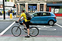 Commuter cyclist in advanced stop lane alongside illegally positioned car, Angel, London Borough of Islington, England, UK, July 2015.