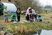 Group of children with their teacher pond dipping in winter, Stoke Newington East Reservoir, now Woodberry Wetlands, London Borough of Hackney, England, UK, March 2010.