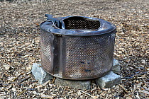 Old washing machine drum recycled as fire pit or basket for barbeque, Dalston Eastern Curve Garden, Hackney, London. UK, April 2016.