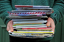 Man&#39;s hands holding pile of catalogues for recycling, Holloway, London Borough of Islington, England, UK, January 2015.