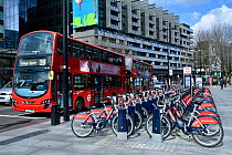 Santander Cycles or Boris Bikes, bicycle hire scheme docking station with number 29 bus, corner of Hampstead Road and Euston Road, Camden, England, UK, March 2016.