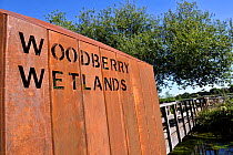 Woodberry Wetlands sign punched on side of rusted iron architecture entrance to urban nature reserve via bridge over New River, formally Stoke Newington Reservoir, Hackney, London, England UK