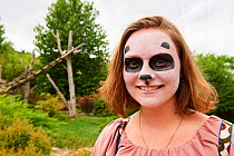 Teenage girl visiting the panda enclosure at the zoo, with panda facepaint. Beauval Zoo, France.  August 2017. Model released.
