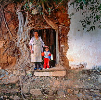 Grandmother and grandson standing next to Strangler fig (Ficus padifolia) covering the wall of their home, Aduana, near Alamos, Sonora, Mexico 1992