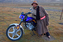 Tibetan shepherd and his motorbike, Tibetan Plateau, Qinghai, China October 2016.