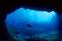 Scuba divers at a  cave entrance, Fernando de Noronha Marine National Park, Brazilian Atlantic Islands UNESCO World Heritage Site, Pernambuco, Brazil, South Atlantic Ocean