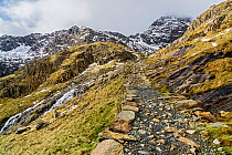 The Miners track up Mount Snowdon with the summit in cloud in the back right and the waterfall from Glaslyn Lake on the left Snowdonia National Park, North Wales, UK, March.