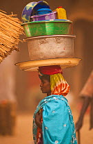 Ouled Rachid tribeswoman carying bowls and buckets on her head, Kashkasha village near Zakouma National Park, Chad, 2010.