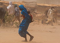 Ouled Rachid tribeswoman with child, looking for shelter at start of a dust storm, Kashkasha village near Zakouma National Park, Chad, 2010.