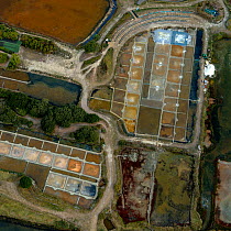 Looking down at salt evaporation ponds and salt piles surrounded by the Salt Marshes of Olonne, Vendee, France, July 2017. The colours are produced by the concentration of algae or halobacteria that l...