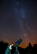 Man looking through a telescope at the night sky, Eifel Dark Sky Park, Eifel National Park, Germany, September 2016.