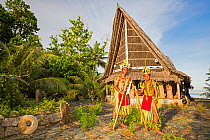 Two young boys in traditional outfits for cultural ceremonies, standing in front of a men's house on the island of Yap, Micronesia. September 2013.