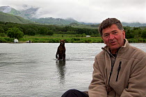 Photographer Michel Roggo on location for the Freshwater project in South Kamtchatka Sanctuary,  with Brown bear (Ursus arctos) fishing for salmon in the background, Ozernaya River, Kuril Lake,  Far E...