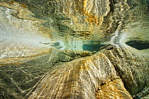 Underwater view of rocks and rippled sunlight in the Verzasca River, Lavertezzo area, Canton Tessin, Switzerland. September. Photographed for the Freshwater Project.