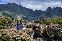 Large group of tourists visiting the Fairy Pools, succession of waterfalls in Glen Brittle on the Isle of Skye,  Scotland, UK, June 2017
