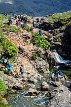Large group of tourists visiting the Fairy Pools, succession of waterfalls in Glen Brittle on the Isle of Skye,  Scotland, UK, June 2017