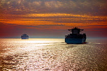Two container ships / cargo vessels sailing at sunset, North Sea