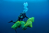 Scuba diver removing plastic marine litter from the sea bed.  Mljet National Park, Mljet  Island, Croatia. May 2015. Model released.