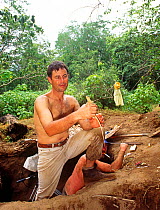 Cameraman Michael Pitts with newly hatched Komodo dragon (Varanus komodensis) at megapode mound where the female  laid her eggs. Komodo Island, Indonesia. 1995