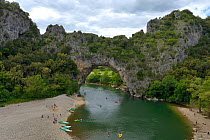 People canoeing under the Pont d'Arc, natural rock arch over river Ardeche, France, May