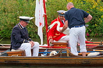 Men carrying Mute swan (Cygnus olor) into row boat during  Swan upping, the annual census and marking of the Swans on the River Thames. England, UK, July 2016.