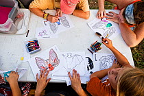 Children learning about Mexican Free-tailed bats (Tadarida brasiliensis), and make 'bat masks' while waiting for the bats to emerge at Bracken Cave. Bracken Cave Preserve, San Antonio, Texas, USA. Jul...