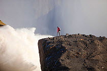 Man standing on cliff near water flowing out of the Karahnjukar dam and Halslon reservoir, a massive new controversial hydro electricity project in North East Iceland. It was created by damming the Jo...