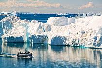 Fishing boat sailing through Icebergs from the Jacobshavn glacier or Sermeq Kujalleq, Greenland, July 2008.