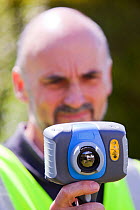 Technician using thermal imaging camera to check the thermal efficiency of a house, and where heat is lost from the house.