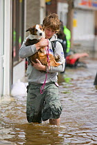 Man with carrying small dog through floodwaters, Bentley, South Yorkshire, England, UK, 28th July 2007.