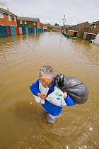 Resident carrying belongings through flood waters,  Toll Bar near Doncaster, South Yorkshire, England, UK, 28th July 2007.