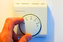 Setting the central heating thermostat at a cooler temperature to save energy.