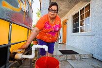 Woman filling a bucket from a tank outside her house supplied by a water charity. The charity supplies water to houses who have had no running water for over five months during the  2012-2017 Californ...