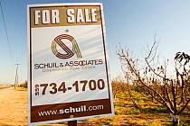 Sign from farmer trying to sell up his land that can no longer grow crops due to the drought. In the background are dying Almond trees that no longer have water to irrigate them. Near Bakersfield, Cal...