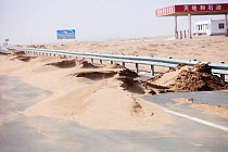 Sand dunes spreading across highway during severe drought,  Inner Mongolia, China. March 2009.