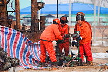 Oil workers drilling a new oil well, Daqing oil field, Northern China, March 2009.