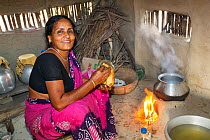 Woman cooking on a traditional clay oven, fuelled by biofuel (rice stalks) Sunderbans, Ganges Delta, Eastern India. December 2013.