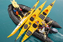 Zodiacs and sea kayaks being lifted off the deck of an expedition cruise ship onto the water, off South Georgia, Antarctica.