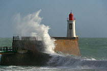 Wave crashing against wall with lightouse, La Chaume, Les Sables d'Olonne, Vendee, France. January