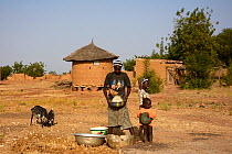 Woman winnowing grain with family, Burkina Faso,  December