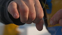 Close-up of a fisherman tying loops in his line, English Channel, near Salcombe, Devon, UK, November 2016.