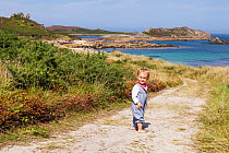 RF - Girl, aged 16 months, standing on path to Little Bay, St. Martin's, looking back, Isles of Scilly. August. Model-released. (This image may be licensed either as rights managed or royalty free.)