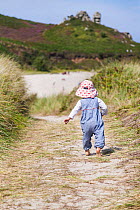 RF - Girl, aged 16 months, walking down path to Little Bay, St. Martin's, Isles of Scilly. August. Model-released. (This image may be licensed either as rights managed or royalty free.)