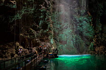 Light shining into Abismo Anhumas or Anhumas Abyss with tourists. This is a 80 metre deep lake, at the bottom of a 72 metre deep cave. Bonito area, Serra da Bodoquena (Bodoquena Mountain Range), Mato...