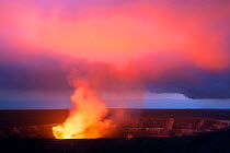 Lava lake hidden the caldera of Halemaumau Crater lights up a plume of steam, sulfur dioxide, and sulfuric acid at dusk, Kilauea Volcano, Hawaii Volcanoes National Park, Hawaii.