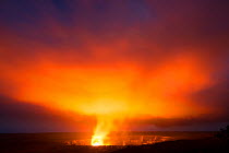 Lava lake hidden the caldera of Halemaumau Crater lights up a plume of steam, sulfur dioxide, and sulfuric acid at dusk, Kilauea Volcano, Hawaii Volcanoes National Park, Hawaii. March 2017.