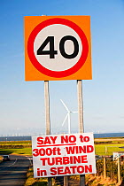 Protest sign about a new wind turbine in Seaton near Workington, Cumbria, England, UK. With onshore wind turbines and the offshore Robin Rigg wind farm visible. January 2012