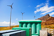 Four wind turbines beneath An Sgurr, Isle of Eigg. Isle of Eigg produces all the energy the island needs from renewable energy. Eigg, Scotland, UK, May.